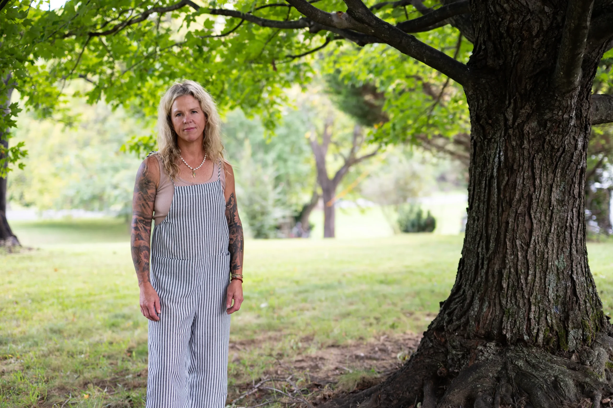 A photo of Stephanie Rowell standing outside her parents' home in the shade of a tree.